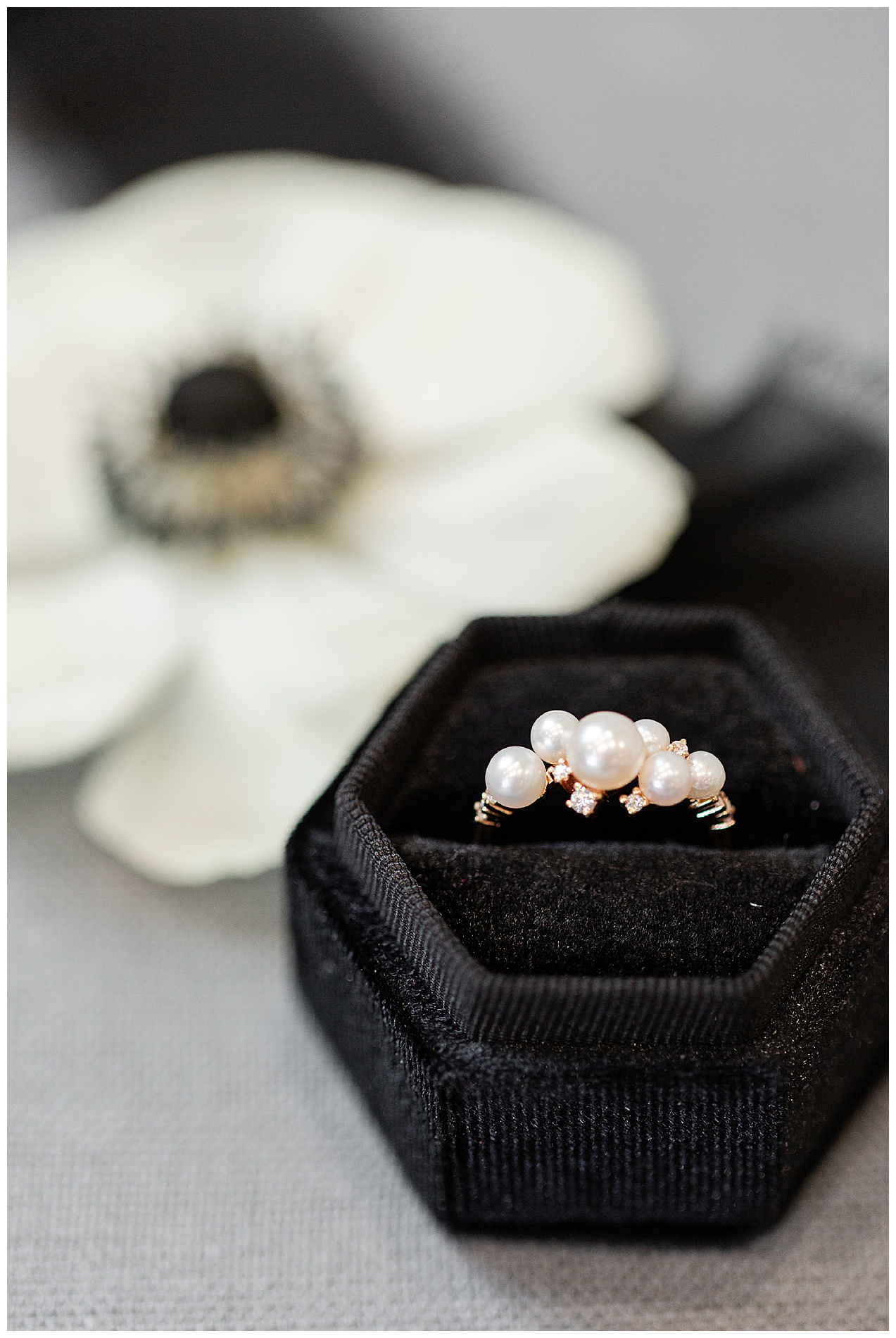 The bride's pearl and diamond ring in a black ring box with an anemone flower in the background
