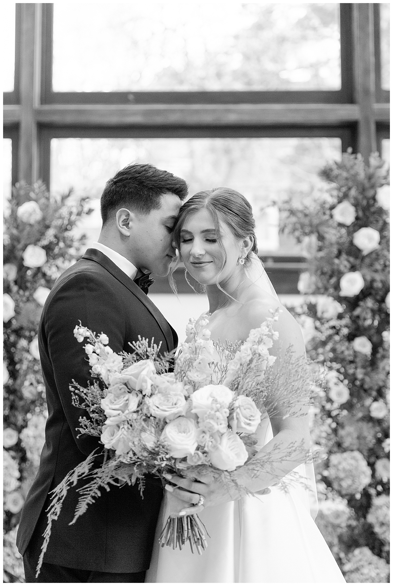 The bride holds her bouquet and the couple appears to be surrounded by flowers
