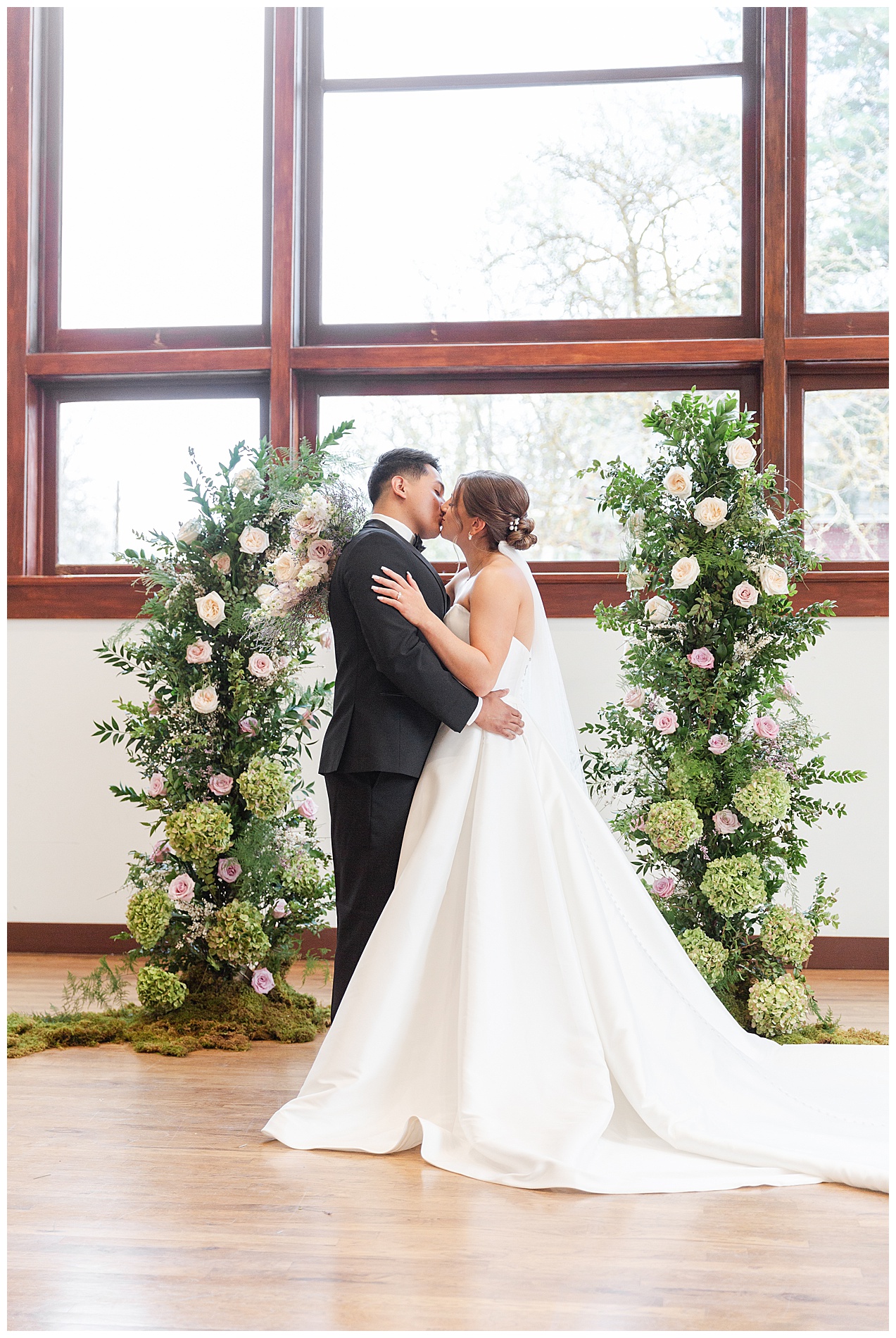The couple kisses in front of the ceremony floral decorations