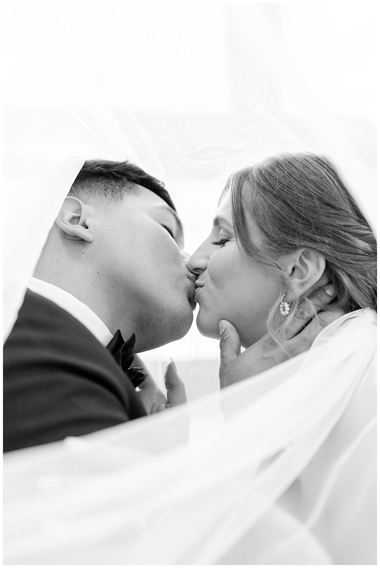 The bride and groom kiss under the bride's long veil