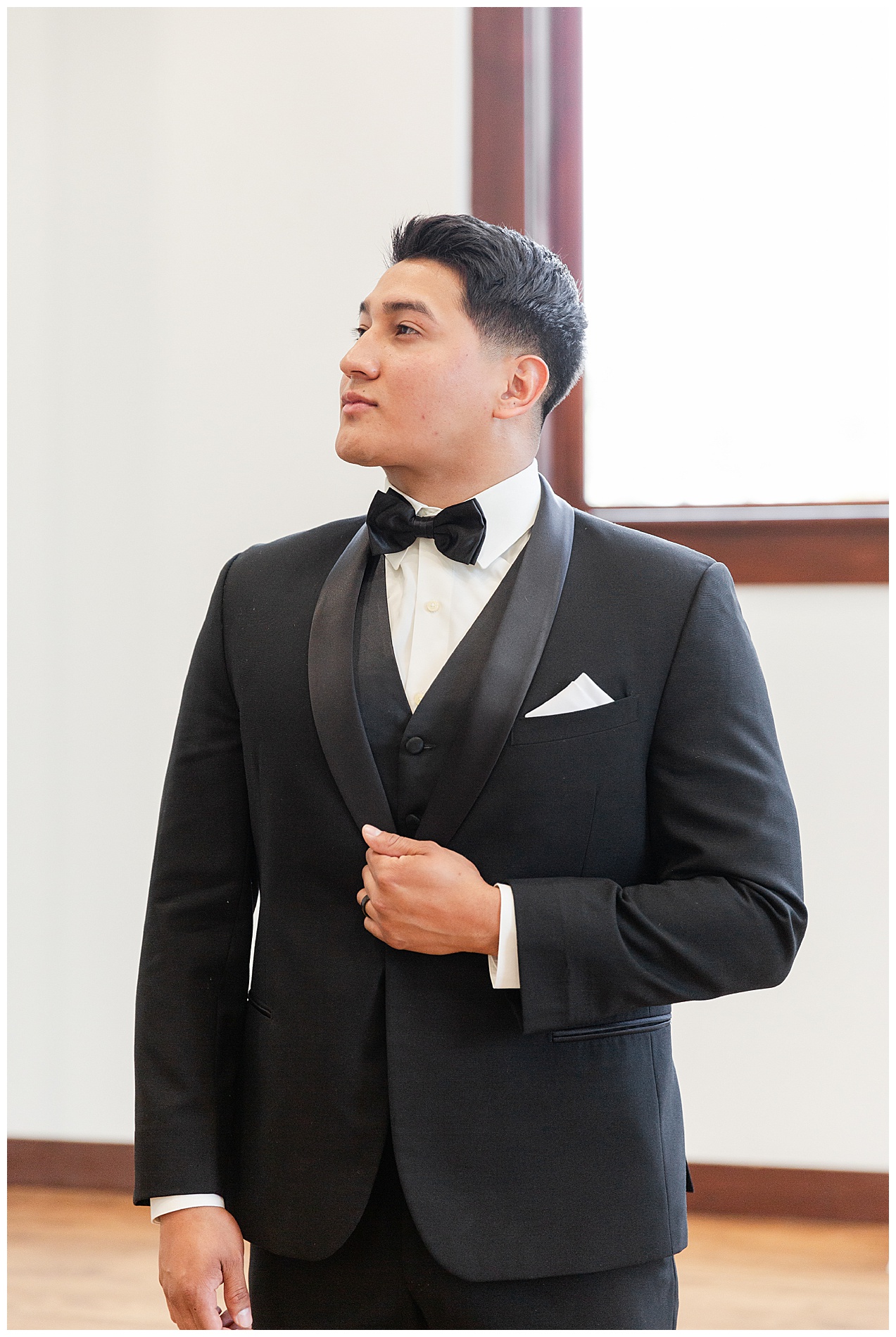 The groom stands looking off to one side
