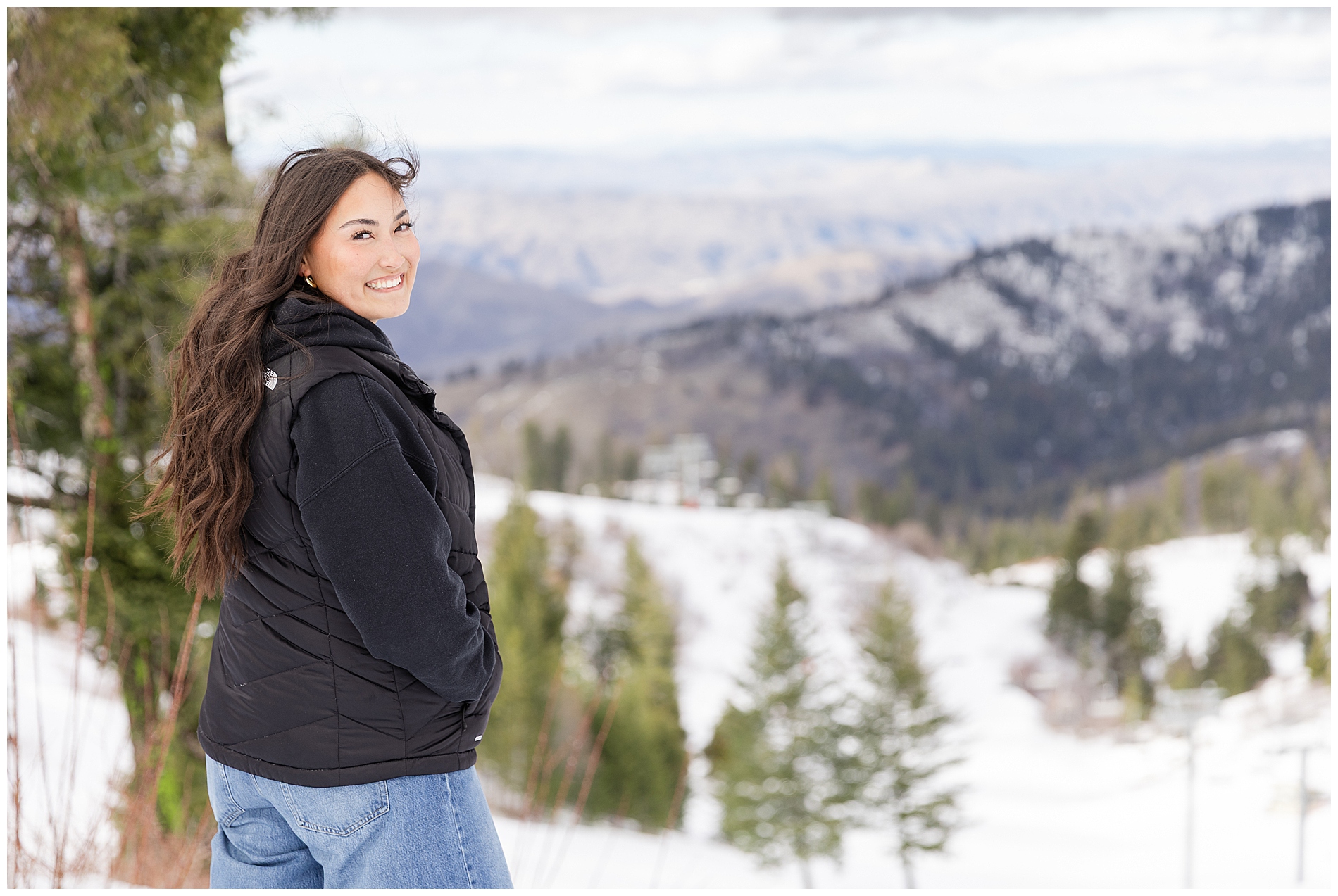 A girl smiles with the view from Bogus Basin behind her