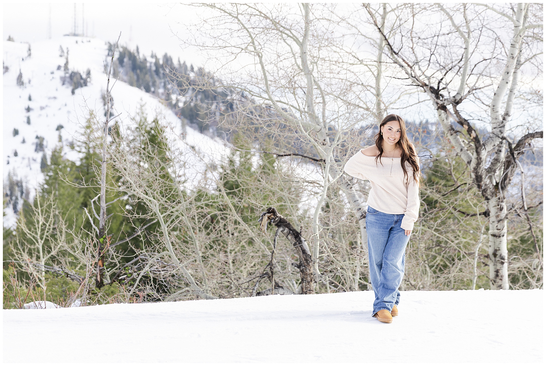 A girl in a sweater and jeans stands in the snow at Bogus Basin
