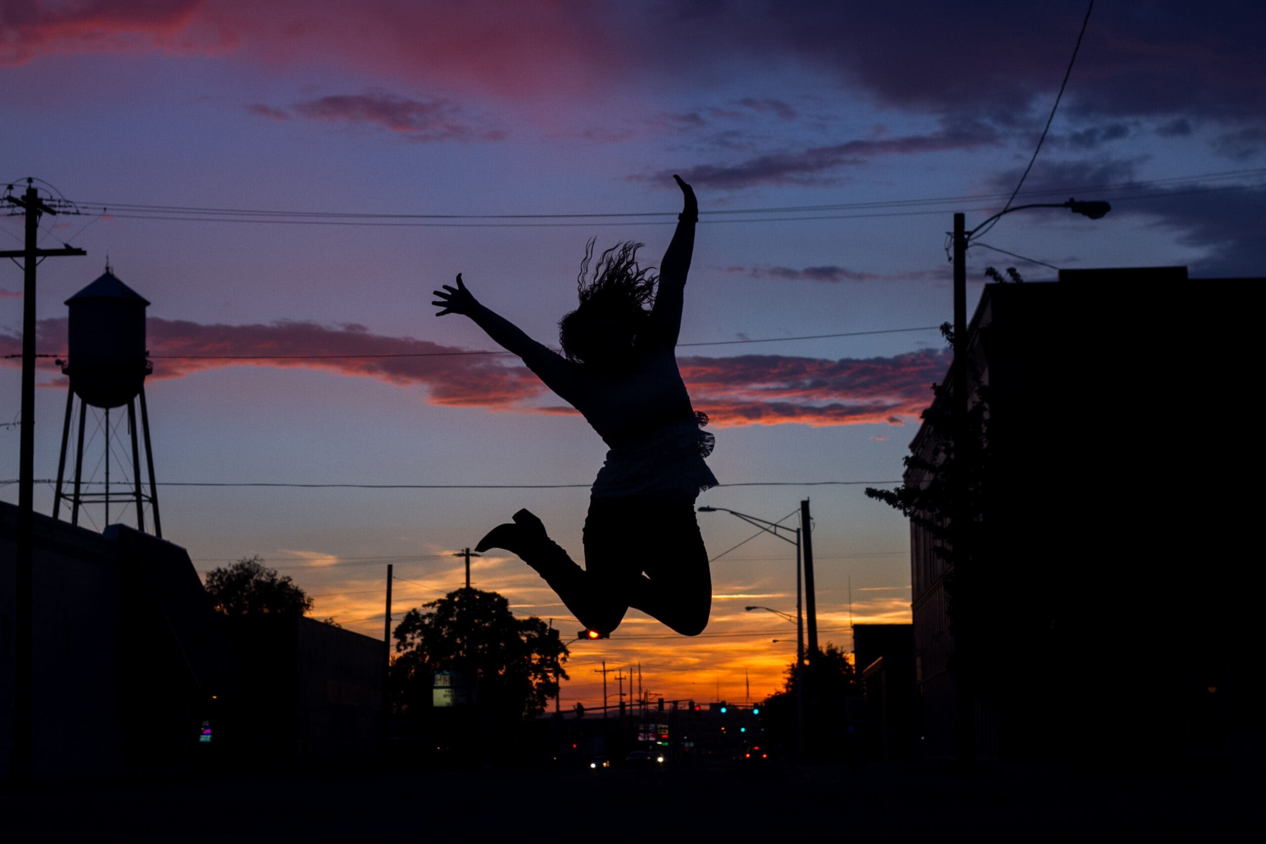 Jumping silhouette with a colorful sunset and buildings downtown