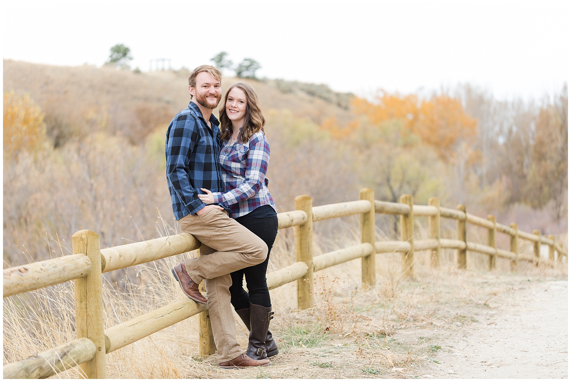 Portrait of an engaged couple with a wooden fence in the background