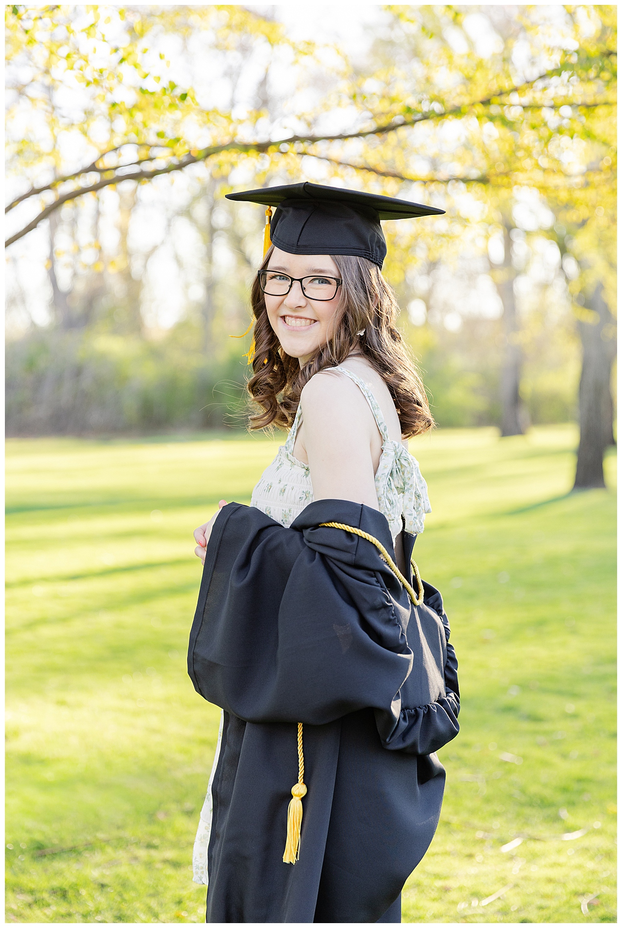 High school senior in her graduation cap and gown in springtime