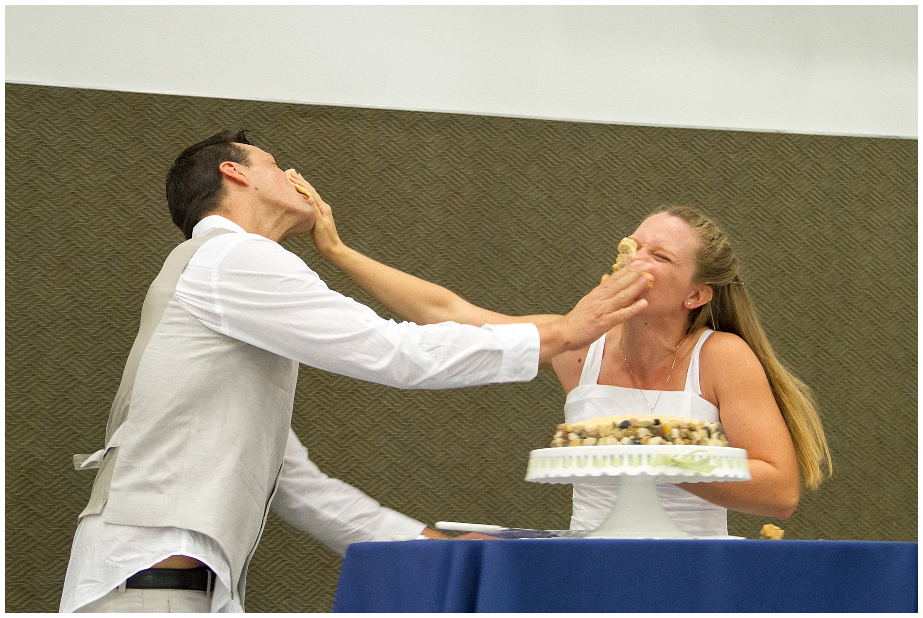 The bride and groom smash their wedding cake into each other's faces at their summer church wedding